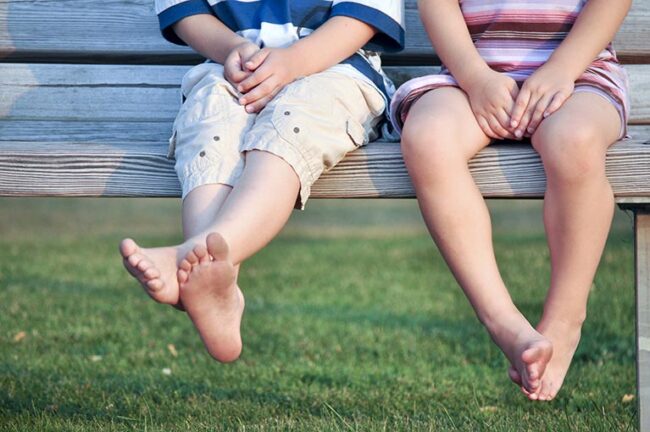 Childrens legs sitting on a bench