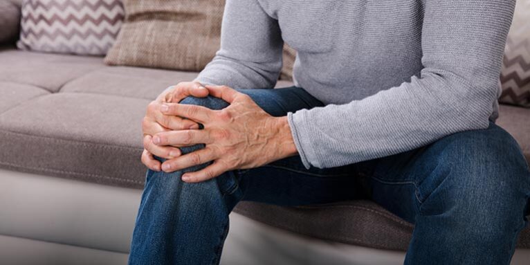 Man with knee pain sitting on sofa