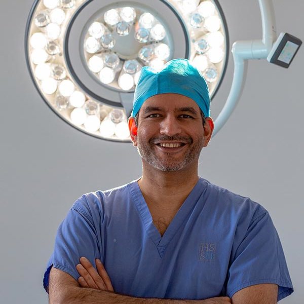 Surgeon smiling with theatre lights behind