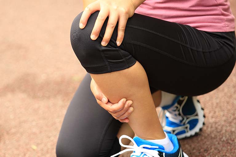 sports woman holding her injured knee